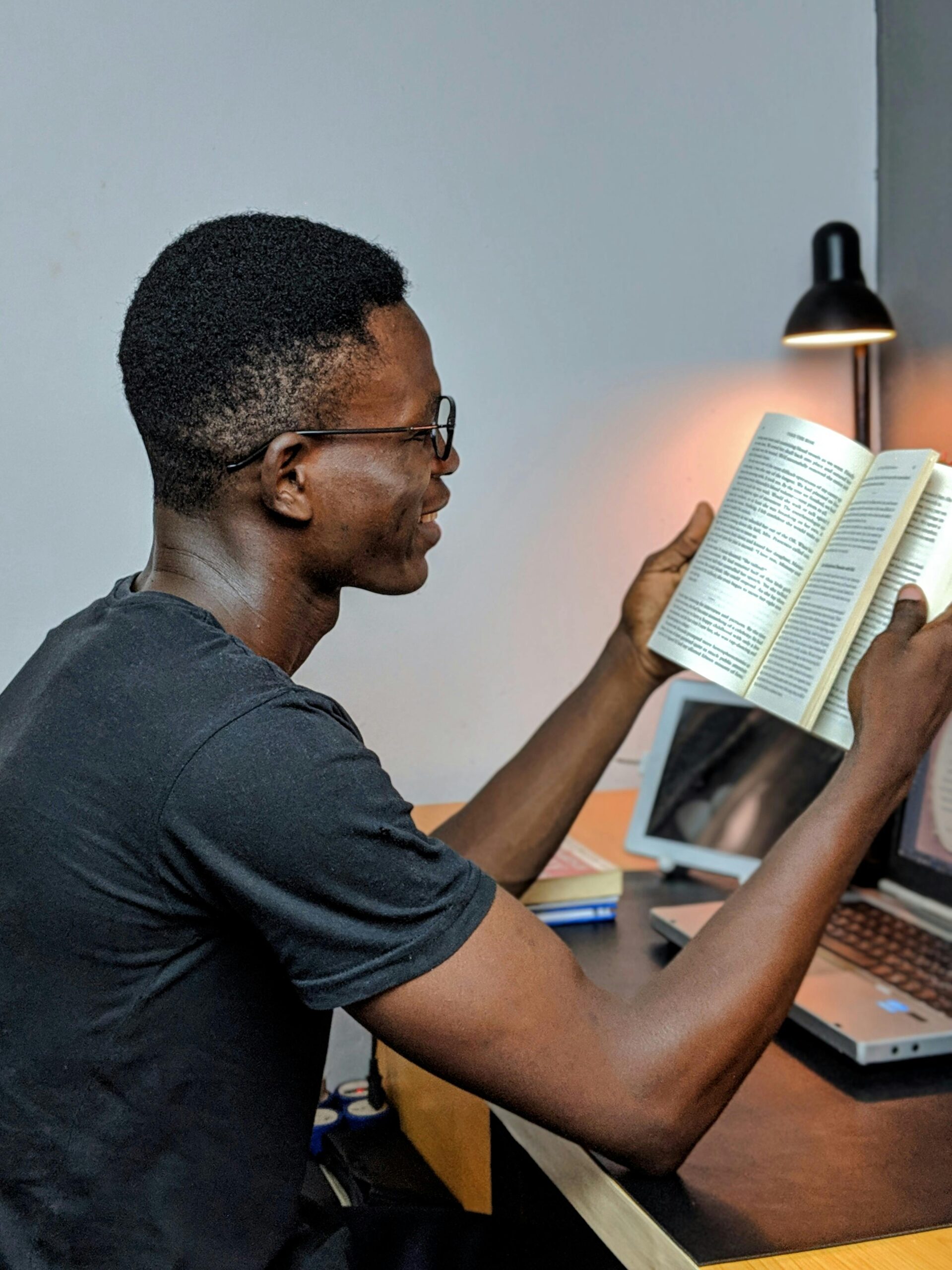 A Nigerian male student wearing gray crew-neck shirt holding a book