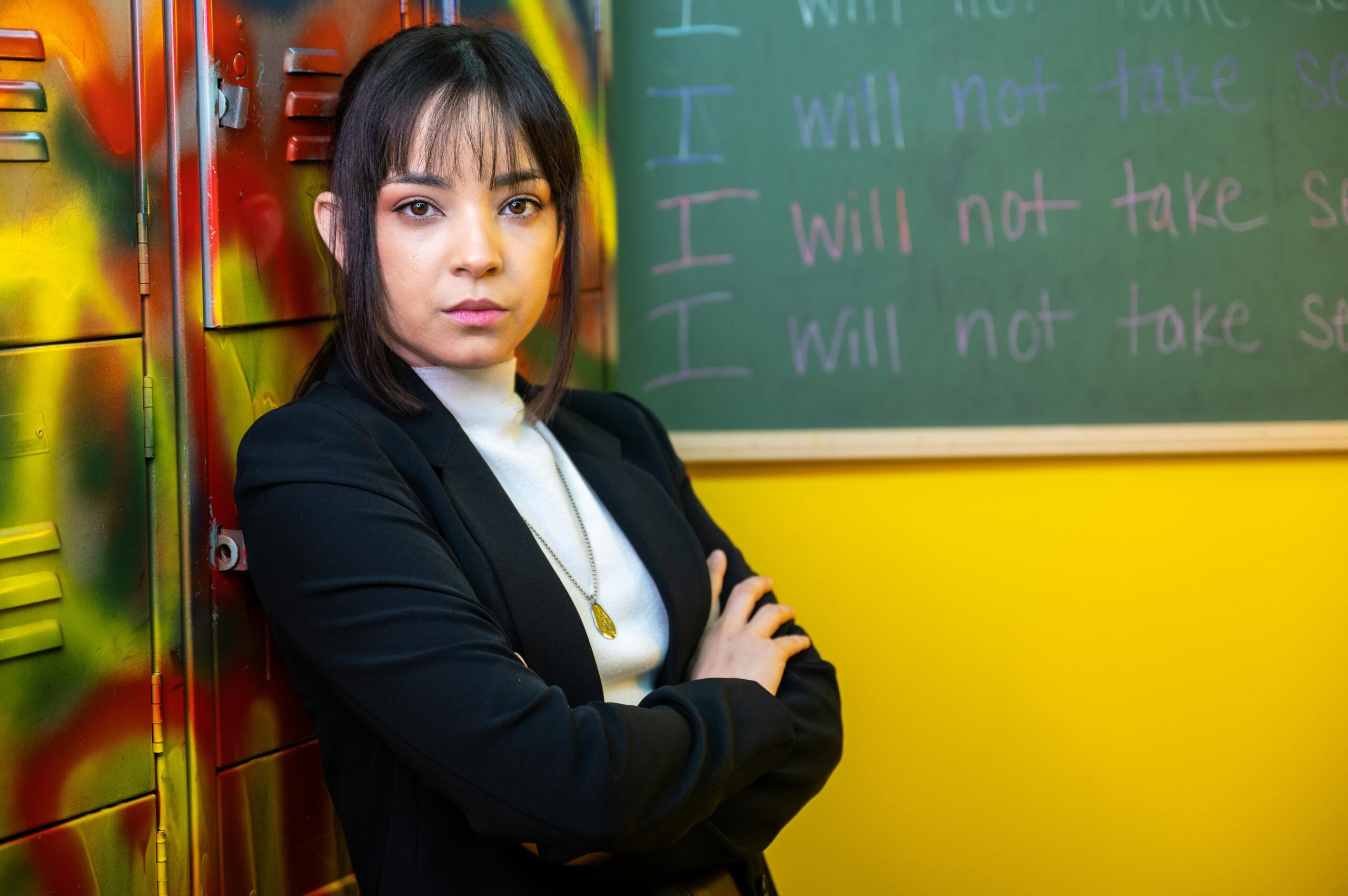 A female student wearing a black blazer standing behind her locker