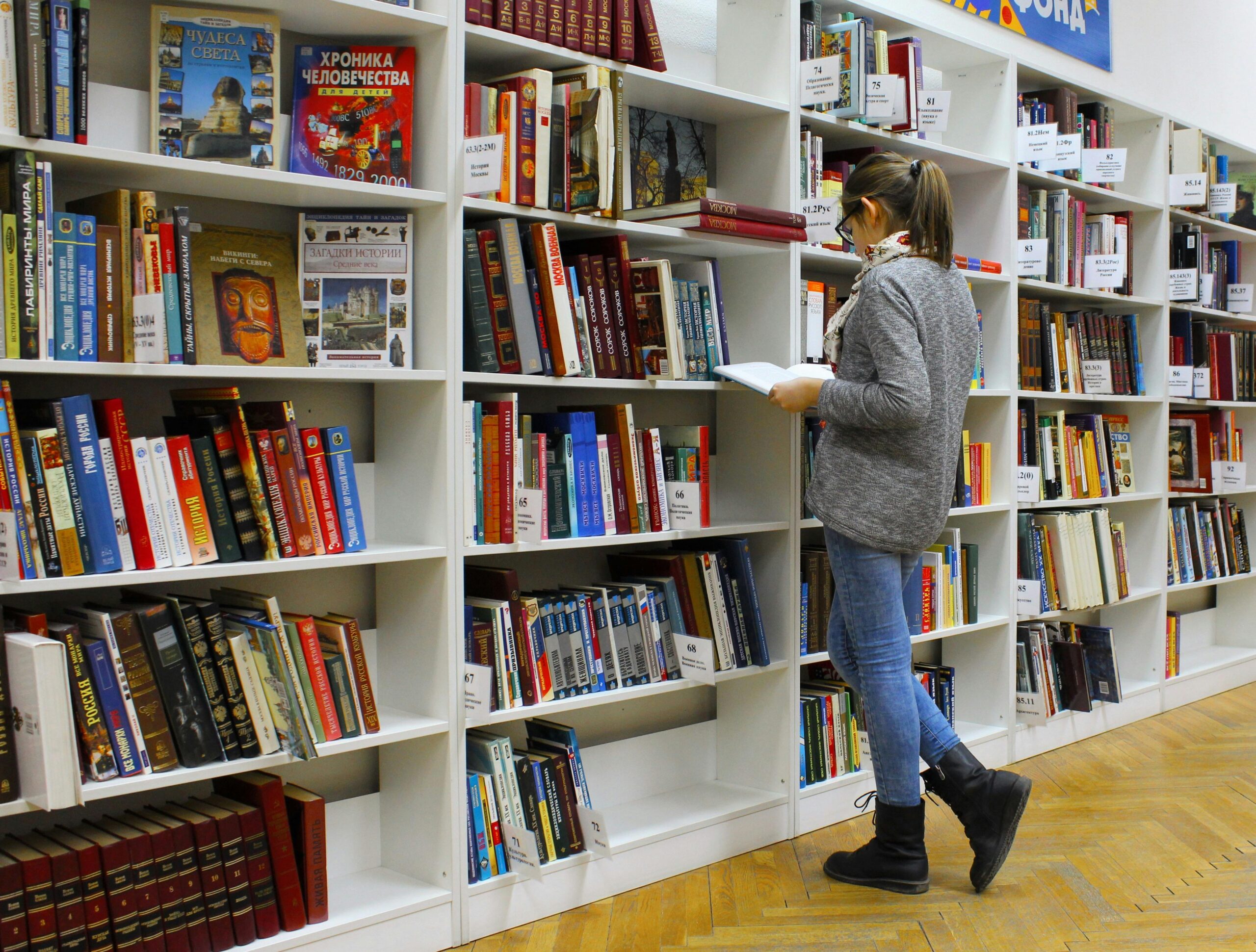 A female student standing and reading books in the library