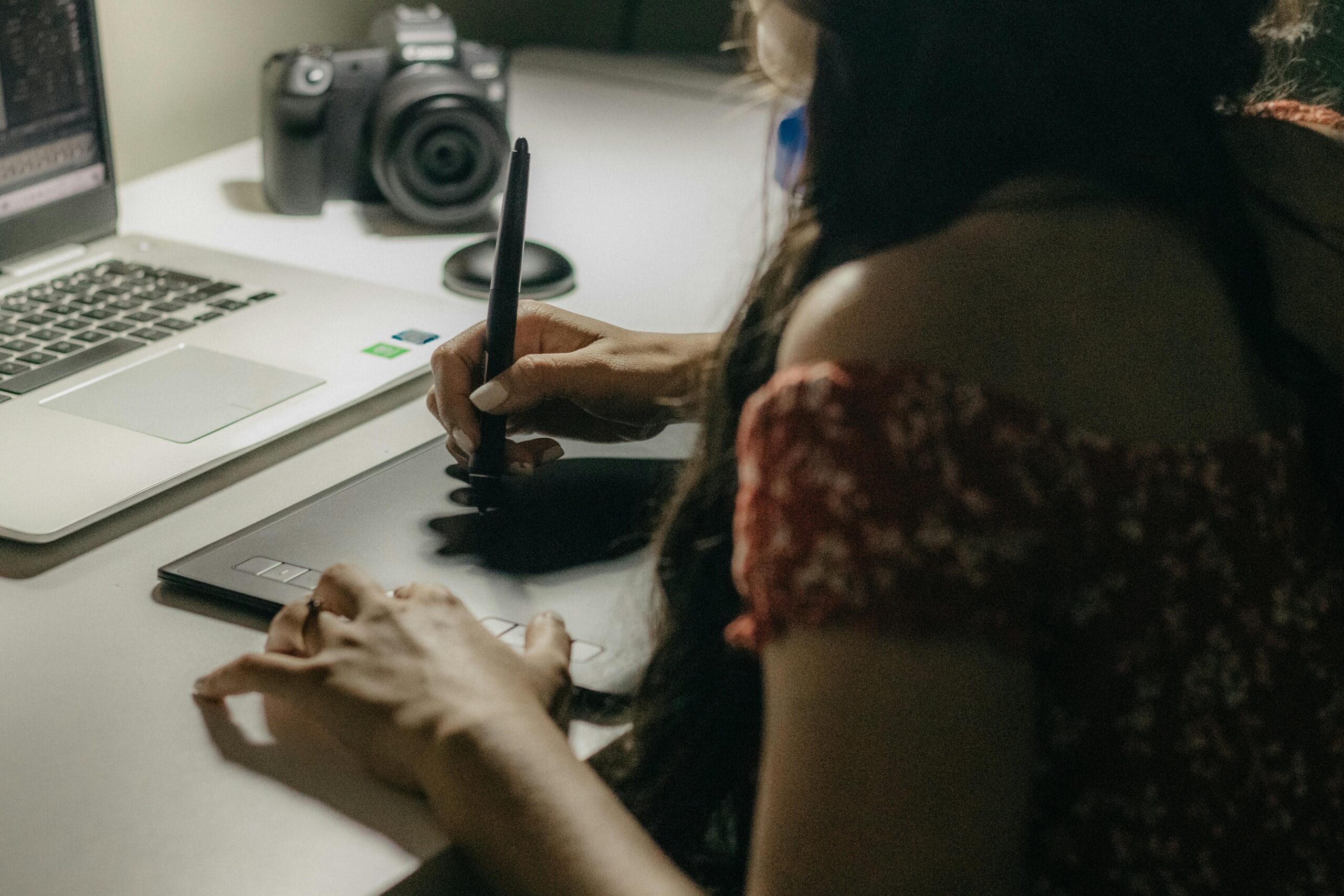 A woman reading something on her laptop and writing a letter on the desk