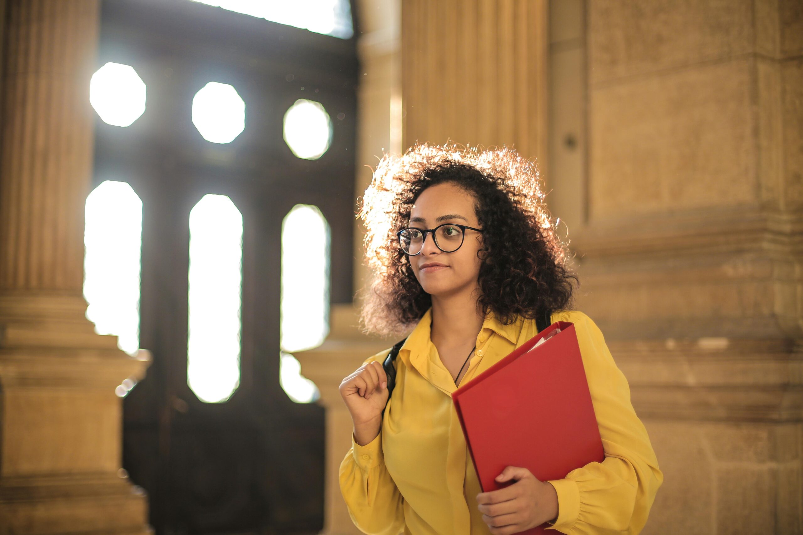 A young female student wearing glasses and Holding Red Book Binder