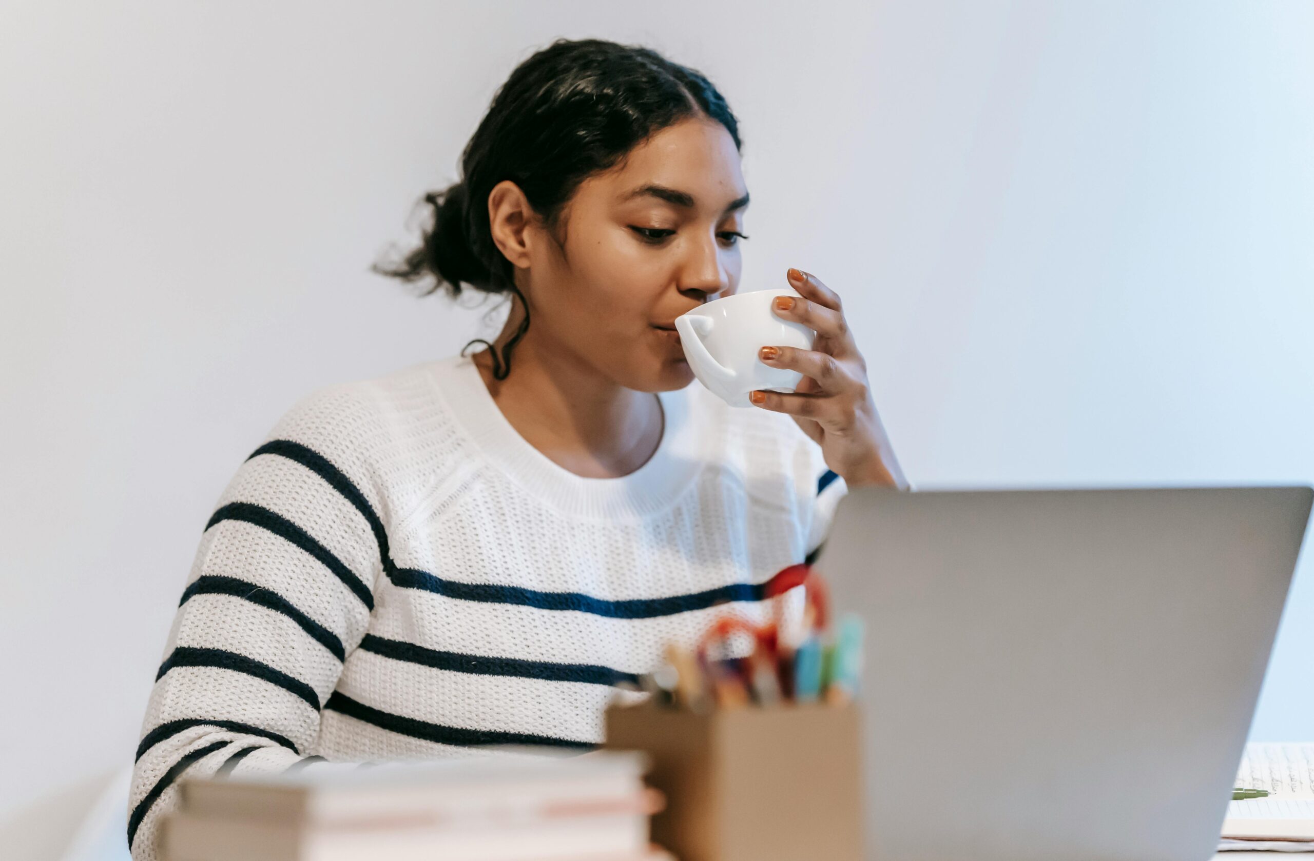 A female student working on her laptop with cup of drink