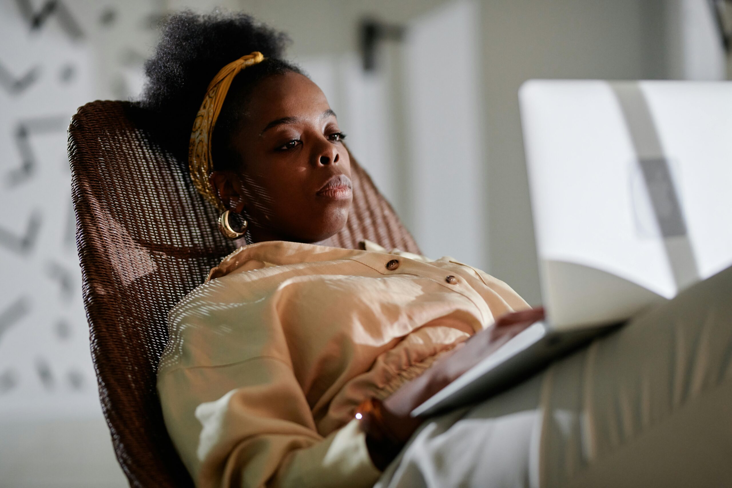 Afro Nigerian female student in Beige Long Sleeve Shirt reading something on her laptop