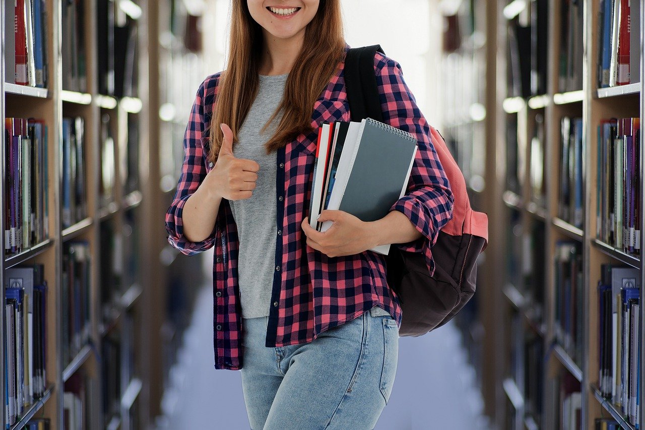 A female student carrying books and walking out from the library