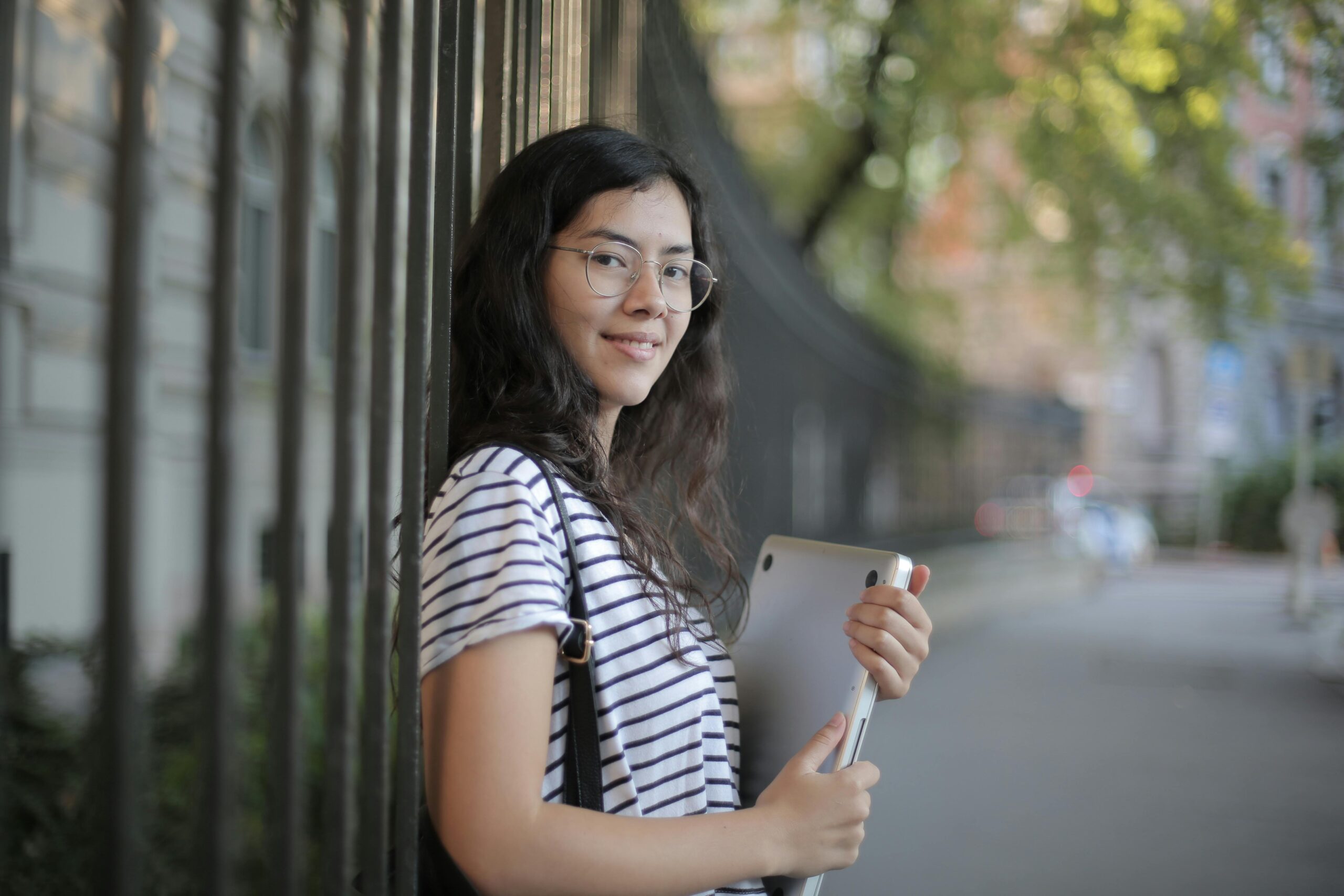 A white female student in Black and White Striped Shirt Holding Laptop