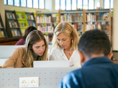 Picture of a focused female student in Canada preparing university project with teacher